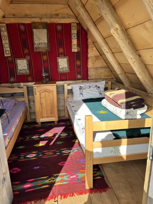 Two wooden beds with embroidered pillows and woven rugs