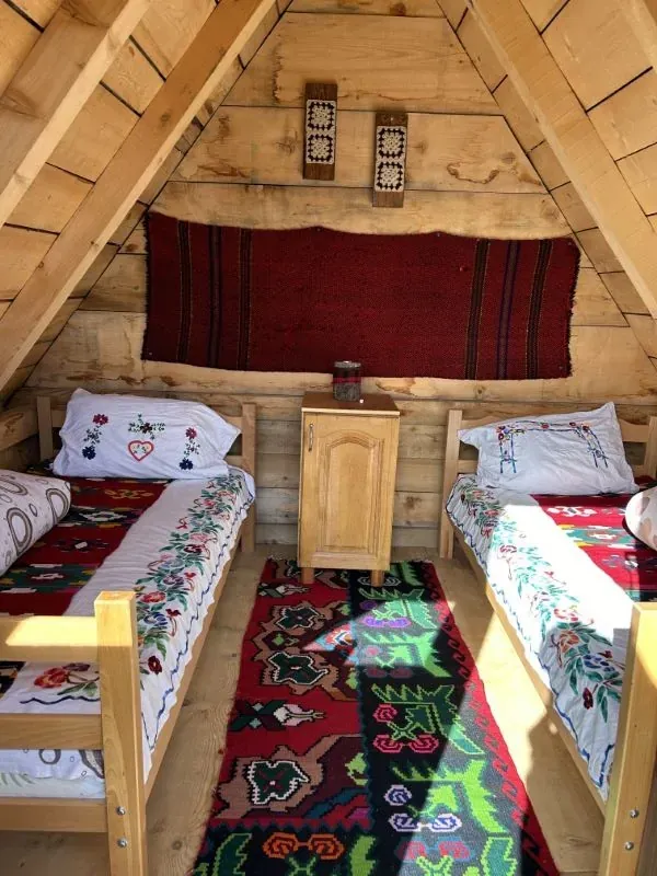 Inside an A-frame cottage with wooden beds and red woven rugs