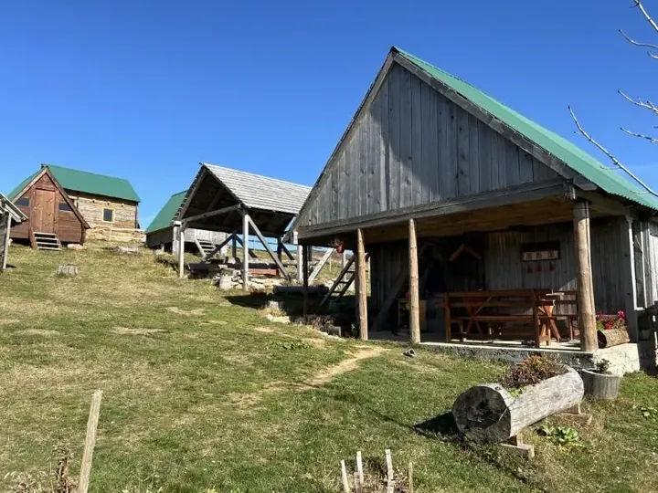 Wooden cottage with a covered porch and green roof on the meadow