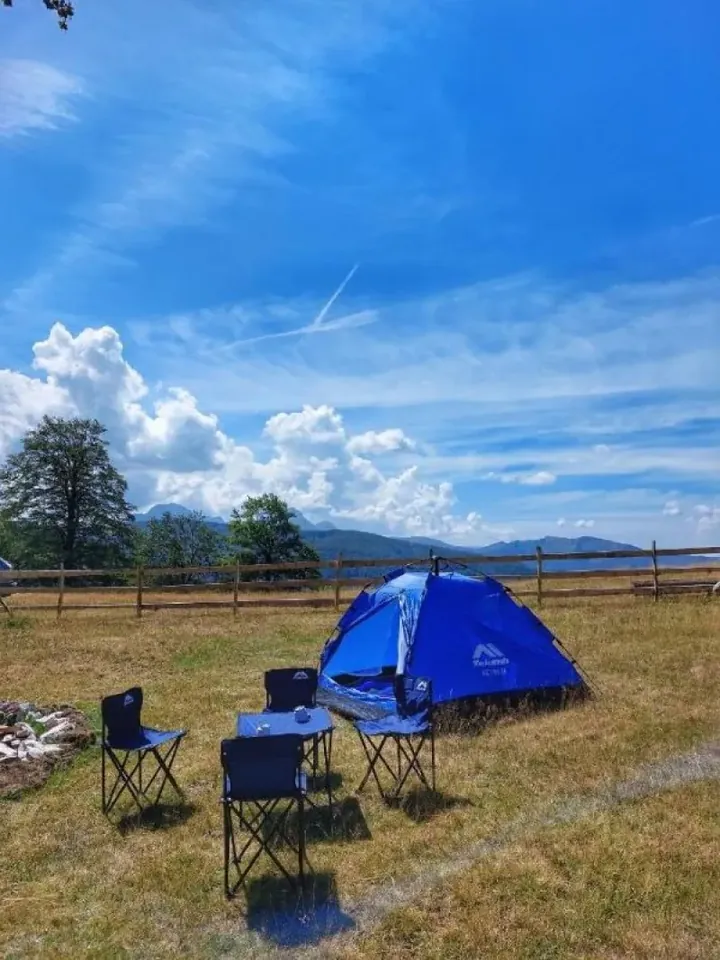 Tent and camping chairs on the meadow